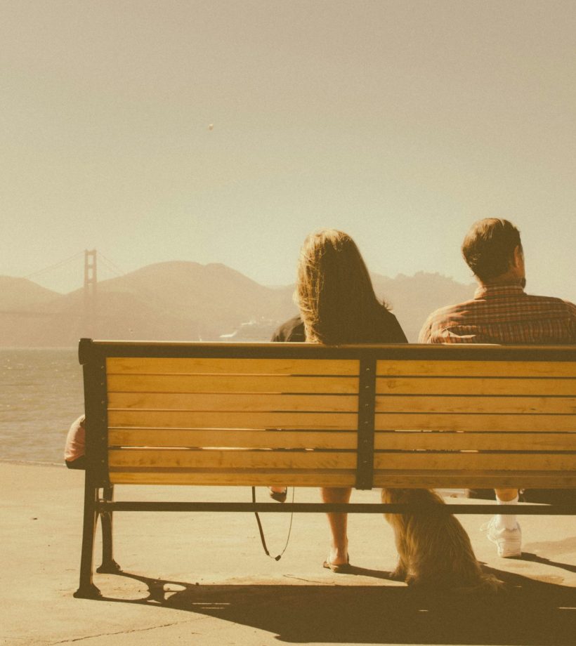 Pareja sentada en un banco mirando al mar, imagen de reflexión y conexión emocional en la terapia de pareja